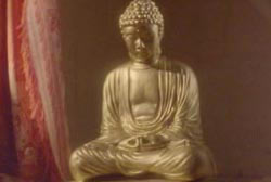 A Golden Buddha placed by a red curtain.