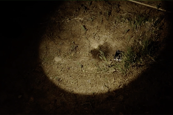 cell phone on ground in flashlight beam