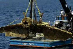 A crane lifts a navy bomber out of the water.