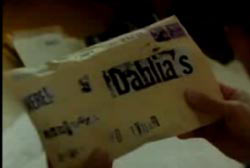 A man holding a stuffed envelope with newpaper cutouts spelling the word 'Dahlias'