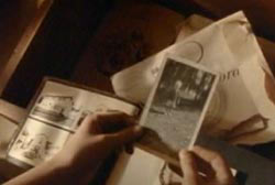 A woman holding a photo of her brother over other old family photos.