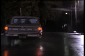 A Ford pick up truck driving down an empty street at night.
