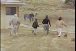 Four local men walking by a house, searching.