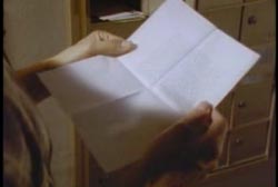 Two hands holding a letter in the light, the writing is ineligible.