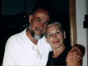 Colleen Wood posing next to her significant other, John Paul. He is a middle aged caucasian man with a black and grey beard.
