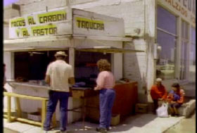 Two people standing next to a taco stand in Mexico.