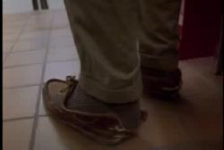A man in standing in shoes that are worn down.