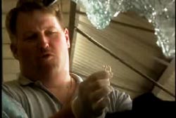 A officer in a polo shirt and wearing medical gloves holds up a ring.