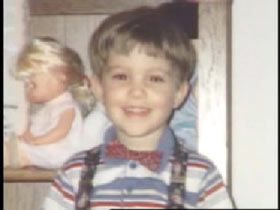 Michael Hughes posing wearing a white shirt, suspenders and tiny red bowtie.
