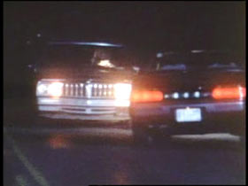A dark road with two cars parked facing each other.