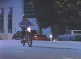 A person wearing a helmet riding a motorcycle down a street.