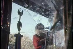 A woman with blonde hair smashing a window from the outside.