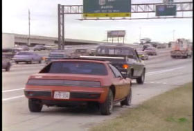 A red compact car parked on the shoulder of a highway.