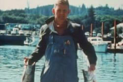 Dexter stands on a dock holding up two large fish.