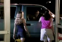 A man talking to two woman from the passenger side window of his blue truck