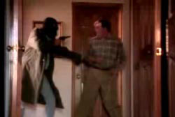 Gunman in a ski mask holding roger by his arm as he points his gun at him