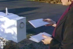 'Sean' putting letters into a white mailbox