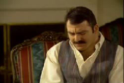 James, sitting on a couch with his head facing down and his eyes closed