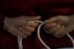 Man with a red shirt holding a rope behind his back