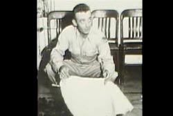 A man in army uniform holding a the white material of a weather balloon