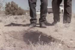 Two soldiers looking at the dusty desert ground