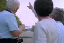 Betty pointing to the sky while John Scheussler writes down notes