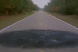 A two lane road in the woods with burn marks in a circular pattern