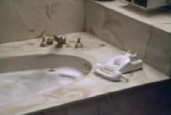 A bathub thats full of water with a landline phone sitting next to it