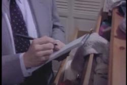 A police investigator writting something on a note pad inside of Charlie's house