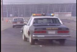 Two police cruisers driving down a highway