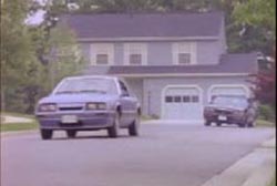 A car driving down the street of a suburban neighborhood