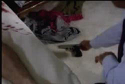 Investigator picking up a small pistol from the floor of a room