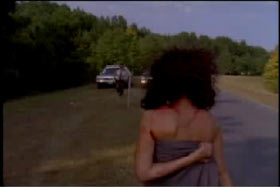 A woman sumbling out of the woods towards a police officer