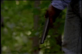 A man holding the barrel of a shotgun 