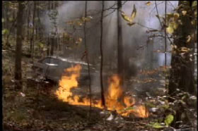 Fire burning behind a station wagon in the woods